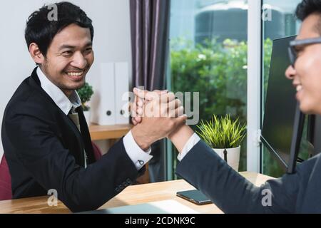 Zwei Geschäftsleute, die sich nach Abschluss der Verhandlungen über den Schreibtisch schüttelten Partnerschaft Stockfoto