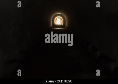 Beleuchteter Ausgang am Ende eines dunklen unterirdischen Tunnels. Stockfoto