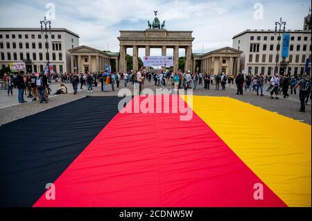 Berlin, Deutschland. August 2020. Vor dem Brandenburger Tor fliegt eine große deutsche Flagge aus Protest gegen die staatlichen Koronamaßnahmen. Quelle: Christophe Gateau/dpa/Alamy Live News Stockfoto