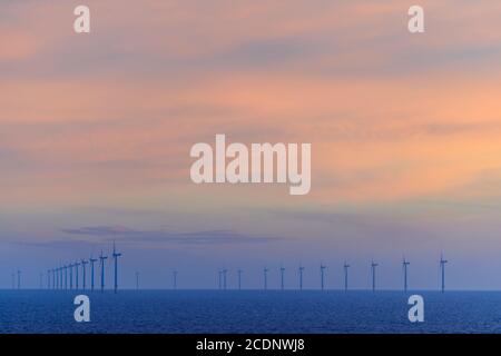 OFFSHORE-WINDPARK HORNSEA, GROSSBRITANNIEN - 2016. JULI 15. Lange Reihe von Windkraftanlagen mit Sonnenuntergang über dem Meer. Stockfoto