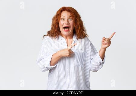 Wow schaut euch dieses Banner an. Aufgeregt und neugierig mittleren Alters Dame diskutieren Werbung, schauen amüsiert und interessiert, Auschecken Banner, zeigen Stockfoto