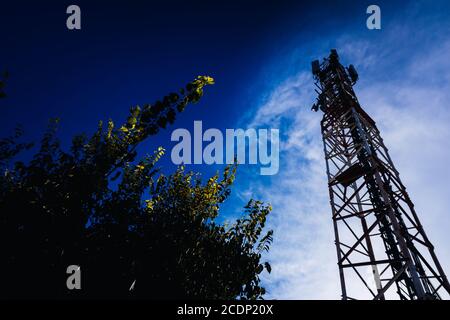 Silhouette eines Telekommunikationsturms mit mobilen Antennen mit Kopierraum auf blauem Himmel Hintergrund. Stockfoto