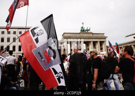 Berlin, Deutschland. August 2020. Auf einer schwarzen, weißen und roten Flagge, die ein Teilnehmer vor dem Brandenburger Tor hält, ist ein Bild von US-Präsident Donald Trump und der Buchstabe Q vor einer Demonstration gegen die Corona-Maßnahmen gedruckt. Quelle: Kay Nietfeld/dpa/Alamy Live News Stockfoto