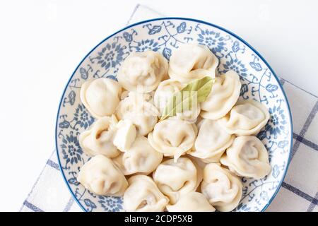 Knödel in einem blauen Teller auf einem karierten Handtuch. Ravioli mit Fleisch. Stockfoto