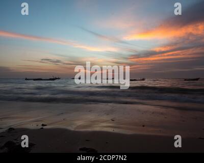 Sonnenuntergang an der Atlantikküste in Afrika und die Silhouetten eines Fischerbootes auf dem Wasser, Senegal, Afrika Stockfoto