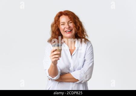 Emotionen, Lifestyle und Freizeitkonzept. Sorglose wunderschöne Erwachsene Rotschopf Frau mit lebhaften Gespräch, reden und lachen, während Kaffee trinken Stockfoto