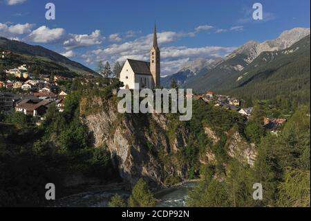 Spätgotische, reformierte Kirche St. George, auf einer Klippe über dem River Inn, in Scuol im unteren Engadintal, Graubünden oder Grisons Kanton, Schweiz. Die Kirche wurde 1516 geweiht, hat aber einen romanischen Turm, der von einer früheren Kirche überlebt hat. Stockfoto