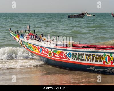 Nianing, Senegal - 24. Januar 2019: Bunte hölzerne Fischerboote stehen am Sandstrand im Senegal. Afrika Stockfoto