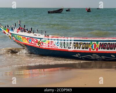 Nianing, Senegal - 24. Januar 2019: Buntes Fischerboot aus Holz, das am Sandstrand im Senegal steht. Afrika Stockfoto