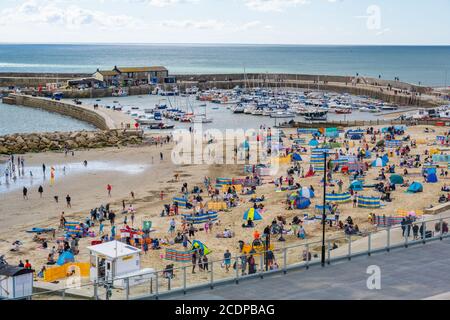 Lyme Regis, Dorset, Großbritannien. August 2020. UK Wetter: Urlauber und Familien strömen an den Strand am Badeort Lyme Regis, um den letzten Sommerurlaub an einem stürmischen Tag mit heißen Sonnenzaubern zu genießen. Kredit: Celia McMahon/Alamy Live Nachrichten Stockfoto