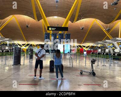 Zwei Touristen schauen sich im Sommer 2020 die Fluginformationsbildschirme am Flughafen Adolfo Suarez Madrid Barajas, Spanien an. Stockfoto