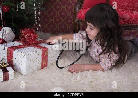 Junges Mädchen in weihnachten Einstellung belauscht auf Geschenkboxen Stockfoto