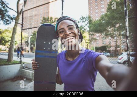 Junges Mädchen, das Tricks mit dem Skateboard in einem Skate park, ein Selfie machen Stockfoto