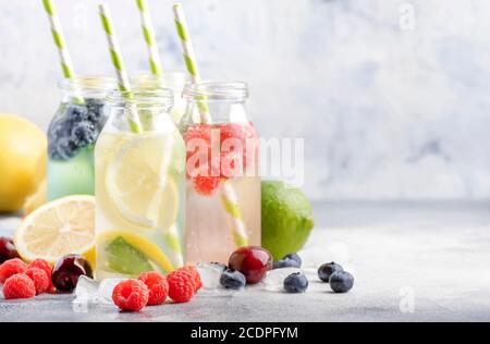 Beere und Zitrusfrüchte infundiert Sommer kalte Getränke in Glasflaschen auf grauen Stein Tisch Hintergrund, kopieren Raum Stockfoto