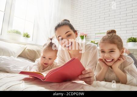 Glücklich liebende Familie. Hübsche junge Mutter Lesung ein Buch zu ihren Töchtern Stockfoto