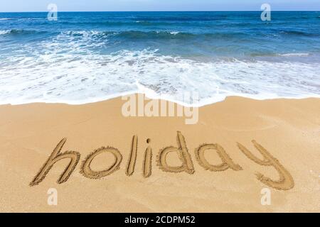 Wort-Urlaub in Sand am Strand geschrieben Stockfoto