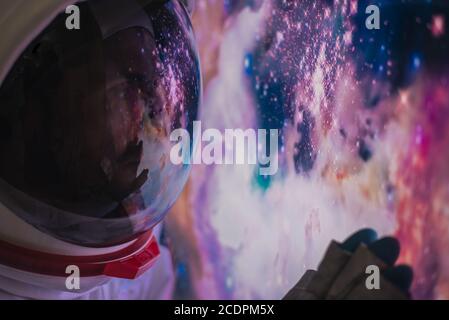 Astronaut schaut aus dem Fenster seiner Kapsel in den Weltraum, die Galaxie und die Planeten. Konzept über Wissenschaft und Weltraumforschung Stockfoto