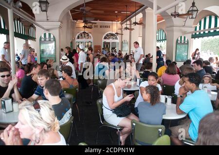 Leute, die an Tischen im Freien im berühmten Cafe Du Monde Coffee Shop auf der Decatur Street im French Quarter von New Orleans, Louisiana, USA, sitzen. Stockfoto