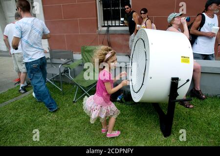 Ein junges Mädchen steht während einer Hitzewelle während eines Straßenfestivals in New Orleans, Louisiana, USA, vor einem großen Kühlventilator. Stockfoto