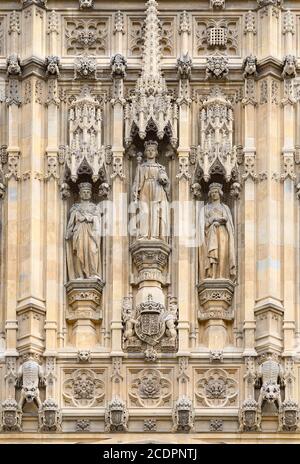 London, England, Großbritannien. Statuen über dem Eingang des Sovereign zu den Houses of Parliament unter dem Victoria Tower. Königin Victoria flankiert von ihrem... Stockfoto