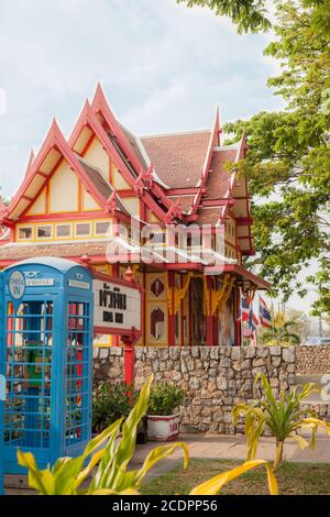 HUA HIN, THAILAND - 2015. FEBRUAR. Blauer Telefonkasten vor dem Bahnhof zusammen mit einem großen grünen Baum. Stockfoto