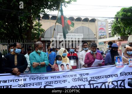 Verwandte halten Porträts ihrer verschwundenen Familienmitglieder, während sie vor dem Internationalen Tag der Verschwundenen im Shahbagh-Gebiet menschliche Ketten bilden Stockfoto