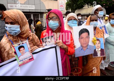 Verwandte halten Porträts ihrer verschwundenen Familienmitglieder, während sie vor dem Internationalen Tag der Verschwundenen im Shahbagh-Gebiet menschliche Ketten bilden Stockfoto