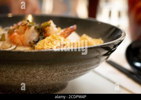 Eine Schüssel Laksa, typische Suppe aus Südost-Asian, die aus Weizennudeln, Huhn, Garnelen und Fisch besteht, serviert in würzigem Curry Kokosmilch Stockfoto