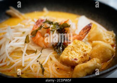 Eine Schüssel Laksa, typische Suppe aus Südost-Asian, die aus Weizennudeln, Huhn, Garnelen und Fisch besteht, serviert in würzigem Curry Kokosmilch Stockfoto