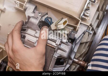 Techniker bei der Reparatur einer Waschmaschine; Nahaufnahme, Motor Stockfoto