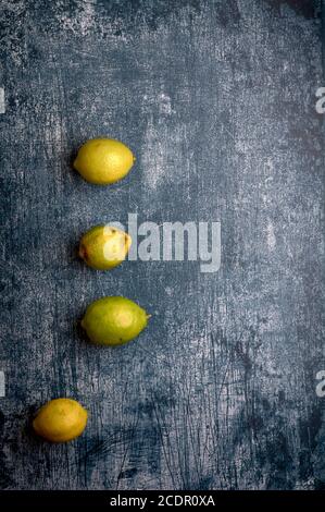 Set aus gelben und grünen Zitronen, geschnitten und ungeschnitten, auf einem blauen, dunklen, metallischen, Zement, Marmor, Stein Hintergrund Stockfoto