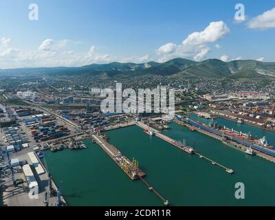 Industrielle Hafenstadt, Ansicht von oben. Hafenkräne und Cargo-Schiffe und Lastkähne. Verladung und Versand der Ladung im Hafen. Blick auf das Meer Stockfoto