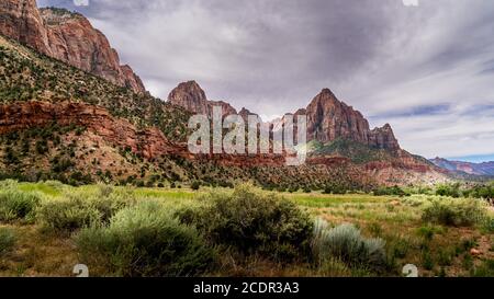 Der Watchman und der Bridge Mountain vom Pa'rus Trail aus gesehen, der entlang und über den Virgin River im Zion National Park in Utah, USA, schlängelt Stockfoto