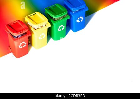 Vier farbcodierte Papierfächer, isometrische Projektion auf geometrischem Regenbogenpapierhintergrund mit Kopierraum. Recycling-Schild an den Behältern - rot, blau, yel Stockfoto