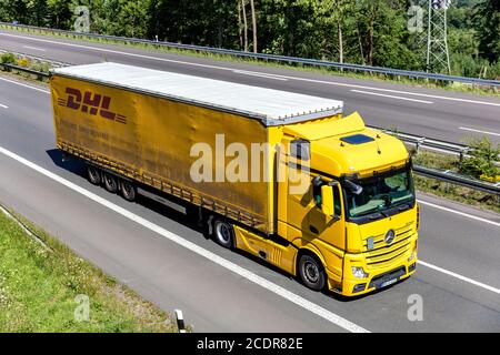 Mercedes-Benz Actros LKW mit DHL Curtainside Anhänger auf der Autobahn. Stockfoto