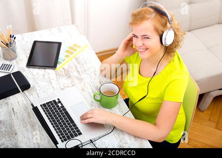 Young plus Größe Frau wiedergeben von Audio während der Arbeit an einem laptop Stockfoto