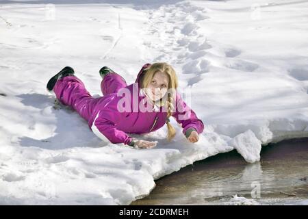 Glückliches Mädchen auf dem Schnee im Winter liegen Stockfoto