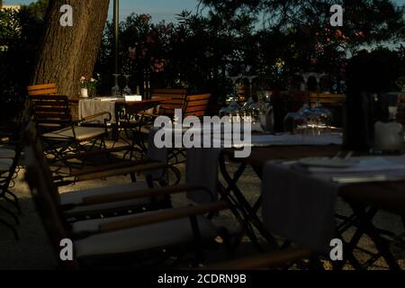 Ein Esstisch wird in einem Küstenrestaurant vor dem Eintreffen des Abendessens in Abendlicht getaucht. Stockfoto