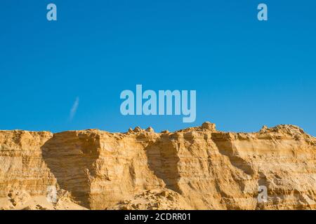 Klippe der gelb orange braun Sand Boden Ton unter den sonnigen Tag mit tiefblauen Himmel Stockfoto