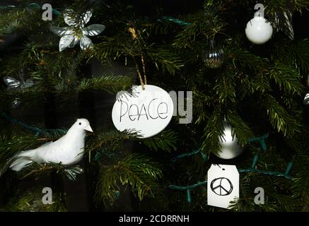 Ornamente, einschließlich einer weißen Taube und Friedenszeichen, schmücken einen Weihnachtsbaum in den Vereinigten Staaten. Stockfoto