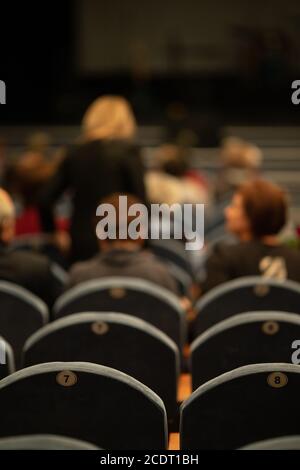 Unschärfe-Unschärfe-Textur, Hintergrund für Design. Die Zuschauer im Theater sitzen vor der Vorstellung auf Stühlen Stockfoto