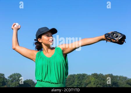 Frau mit Handschuh und Kappe werfen Baseball draußen Stockfoto