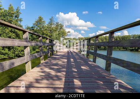 Lange Holzbrücke über Wasser des Teiches Stockfoto