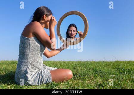 Frau Anwendung Kosmetik Mascara Make-up im Spiegel draußen Stockfoto