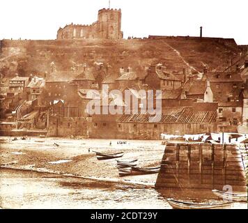 In Bram Stokers Roman Dracula landete das von ihm heimgesuchte russische Schiff Demeter aus Varna am Tate Hill Beach, Whitby, Yorkshire - Diese frühe Fotografie von Tate Hill Beach und Pier, Whitby, Nth Yorkshire, UK, zeigt beides, wie sie es zu Bram Stokers Zeit gewesen wären. Auf der Klippe dahinter kann man die Pfarrkirche der Heiligen Maria sehen, die über 199 Stufen erreicht wird. Heute haben sich viele der Gebäude an der Küste verändert oder sind ganz verschwunden. Stockfoto