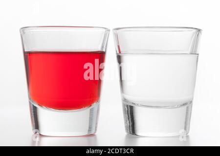 Zwei Gläser Alkohol. Eine rote aromatisierte, die andere saubere Wodka. Stockfoto