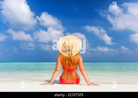 Schöne junge Frau in Sonnenhut sitzen entspannt am tropischen Strand Auf den Malediven Stockfoto