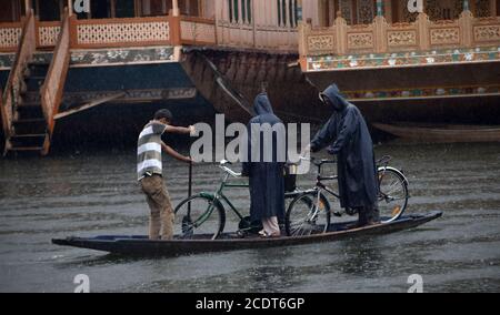 Menschen, die während heftiger Regenfälle auf einem Floß in Srinagar, Indien, unterwegs sind. Stockfoto