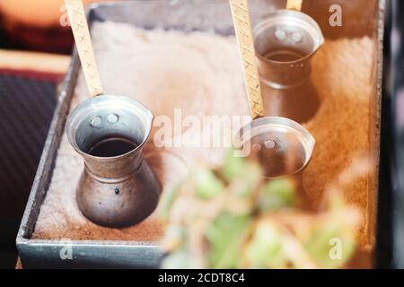 Zubereitung von türkischem Kaffee in die Cezve im Sand an der Cafébar Stockfoto