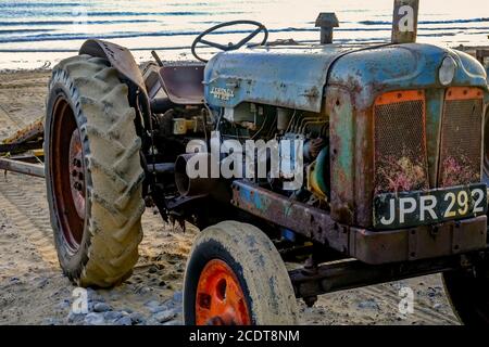 Ein rostiger alter Traktor am Cromer Strand an der North Norfolk Coast bei Sonnenaufgang. Traktoren, wie dieser, werden verwendet, um die Fischerboote zum Shorelin zu bringen Stockfoto